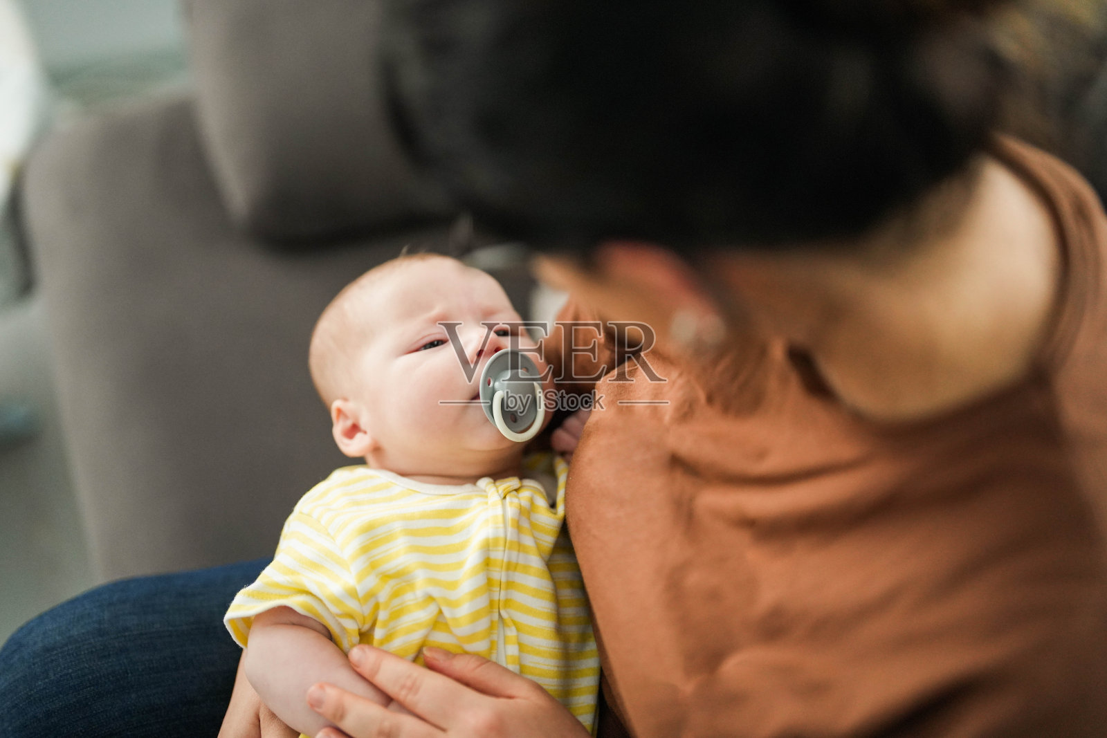 客厅里，刚出生的婴儿睡在妈妈的腿上照片摄影图片