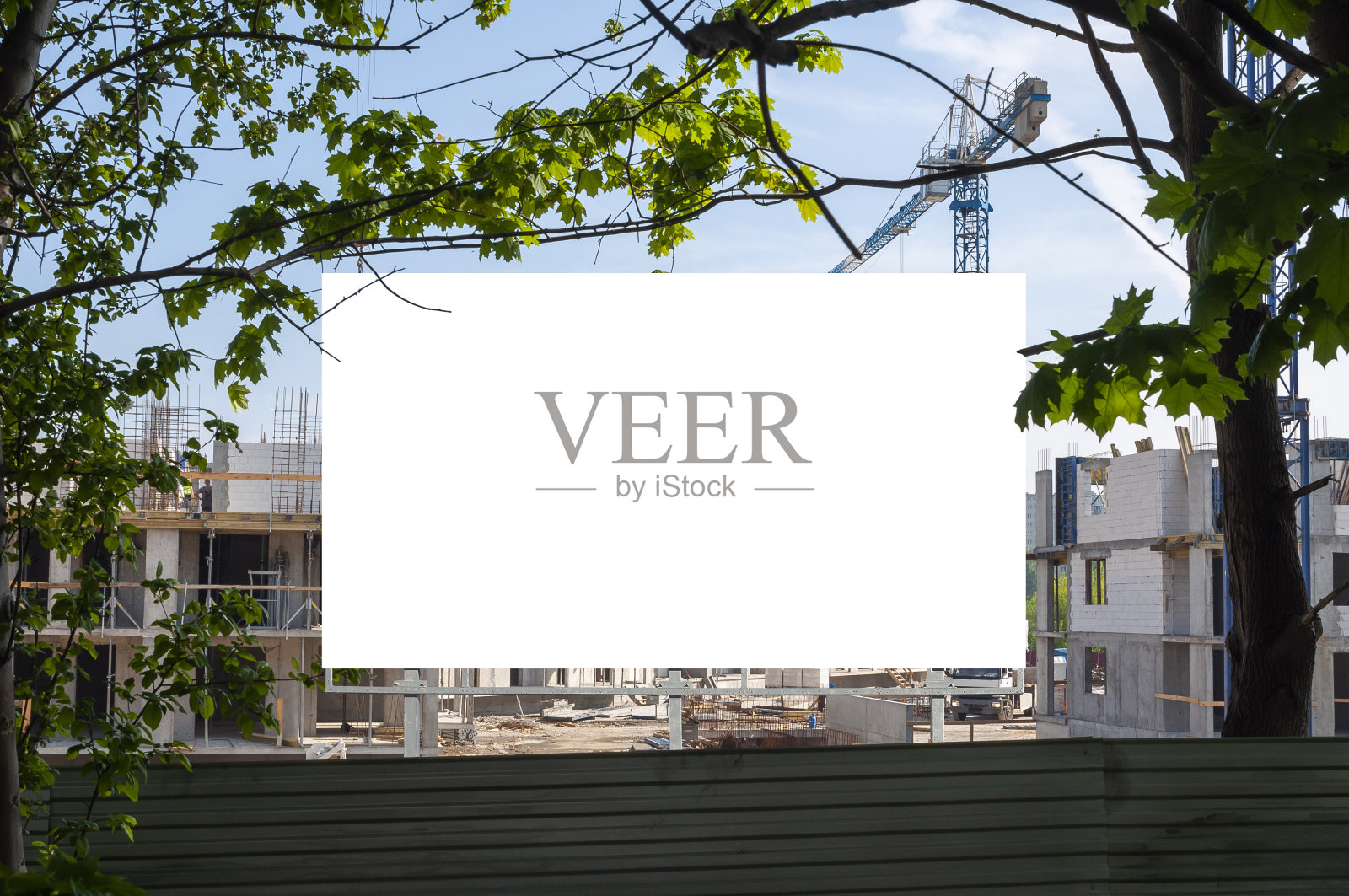 建筑工地前的空白广告牌。一个阳光明媚的日子，公寓正在建设中。照片摄影图片