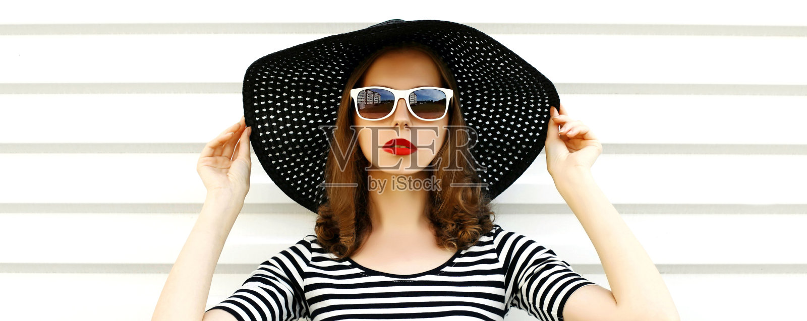 肖像美丽的女人模型戴着黑色圆形夏季帽子，条纹裙在白色背景照片摄影图片