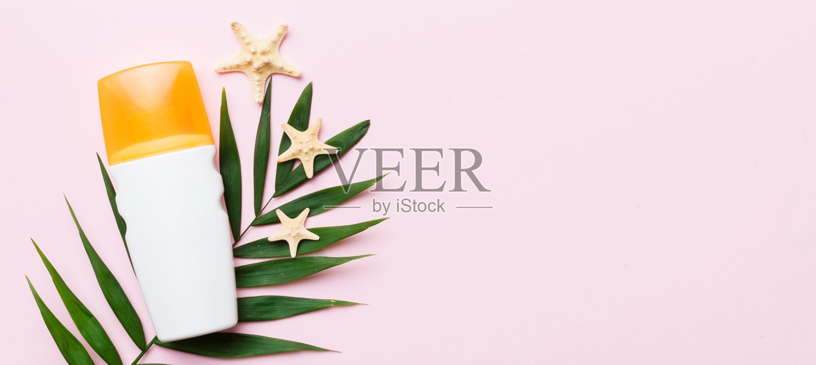 防晒喷雾瓶。瓶子与防晒霜和海洋贝壳与热带绿叶在彩色背景，俯视图照片摄影图片