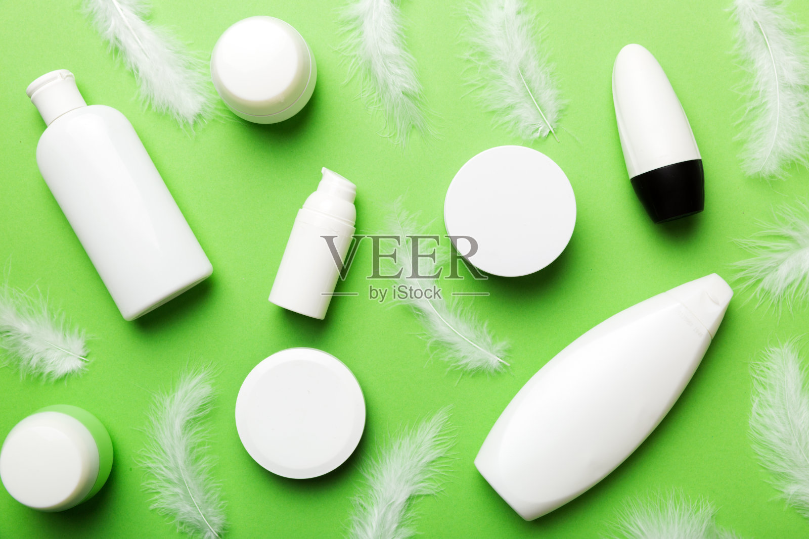 Spa化妆品，面霜罐，品牌模型，羽毛背景俯视图。平躺照片摄影图片