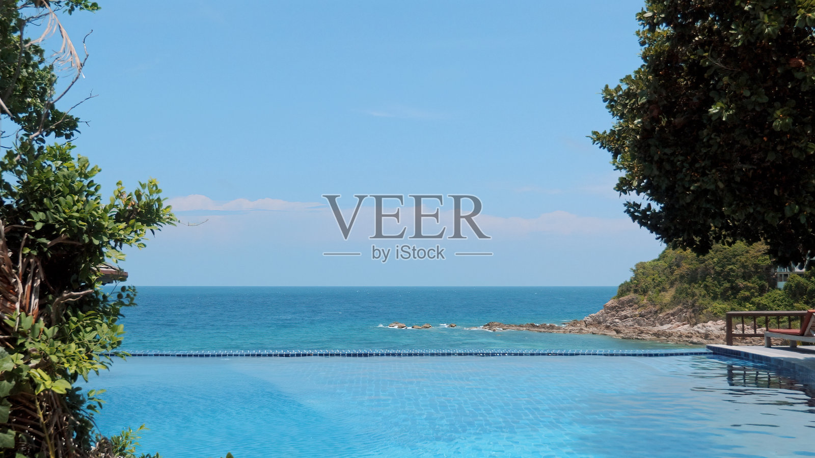 从无边泳池俯瞰绿松石海的壮丽景色。照片摄影图片