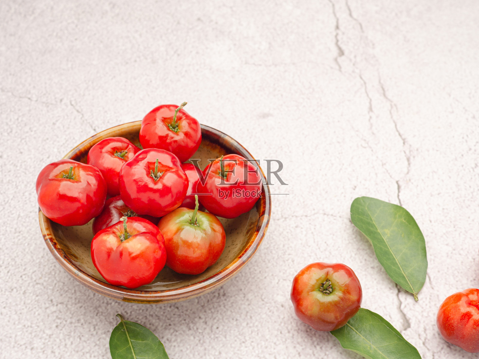 成熟的红色针叶樱桃果实在陶瓷碗和绿叶照片摄影图片