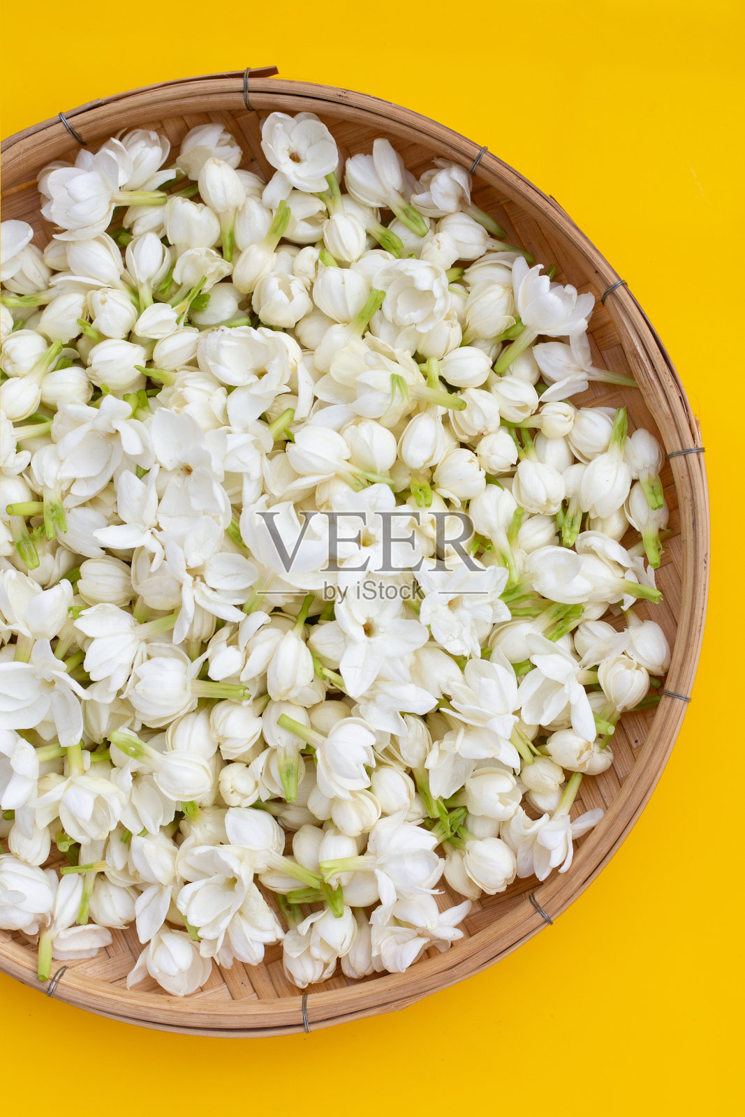 黄色背景的泰国茉莉花竹编盘。照片摄影图片