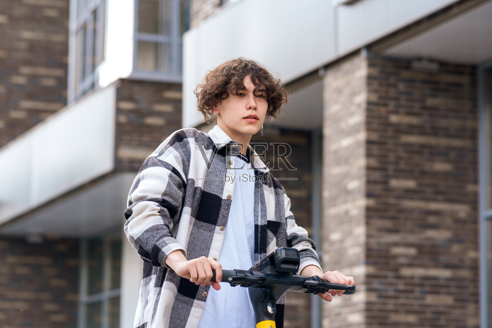 一个年轻人骑着电动滑板车沿街而行照片摄影图片