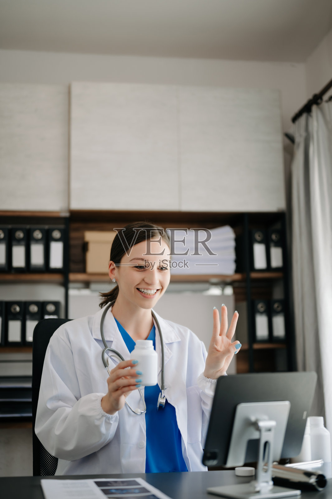 有魅力的女医生一边在办公室用笔记本电脑视频通话一边向病人解释治疗方法照片摄影图片