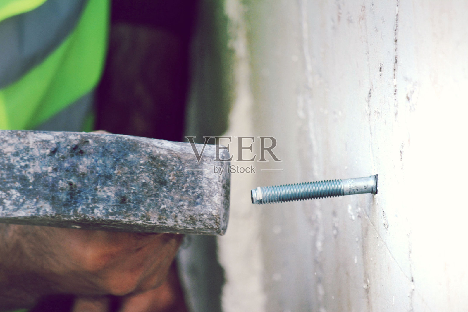用锤子把东西钉在墙上的人照片摄影图片