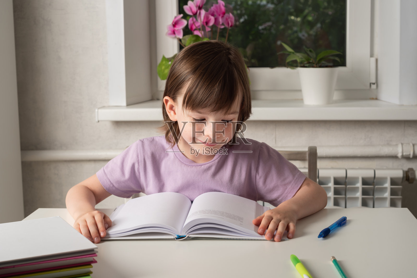 回到学校。这个女孩正坐在桌旁看书。照片摄影图片