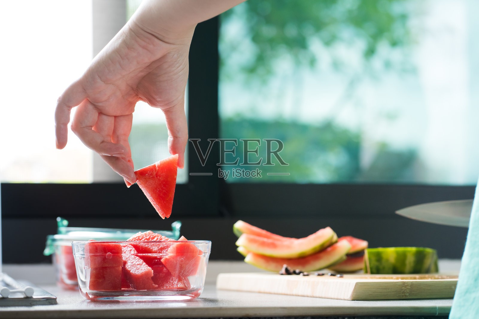 妇女在厨房的木板上用小刀切西瓜照片摄影图片