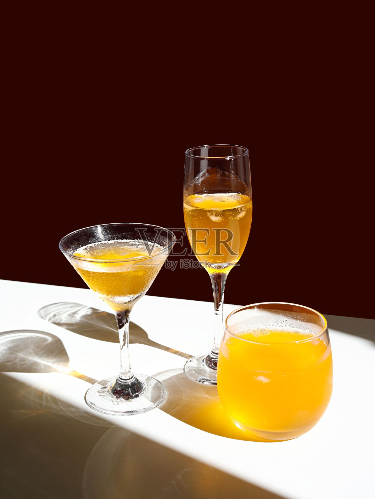 明亮的房间里，白色的桌子上放着一个装满浅色饮料的透明玻璃杯照片摄影图片