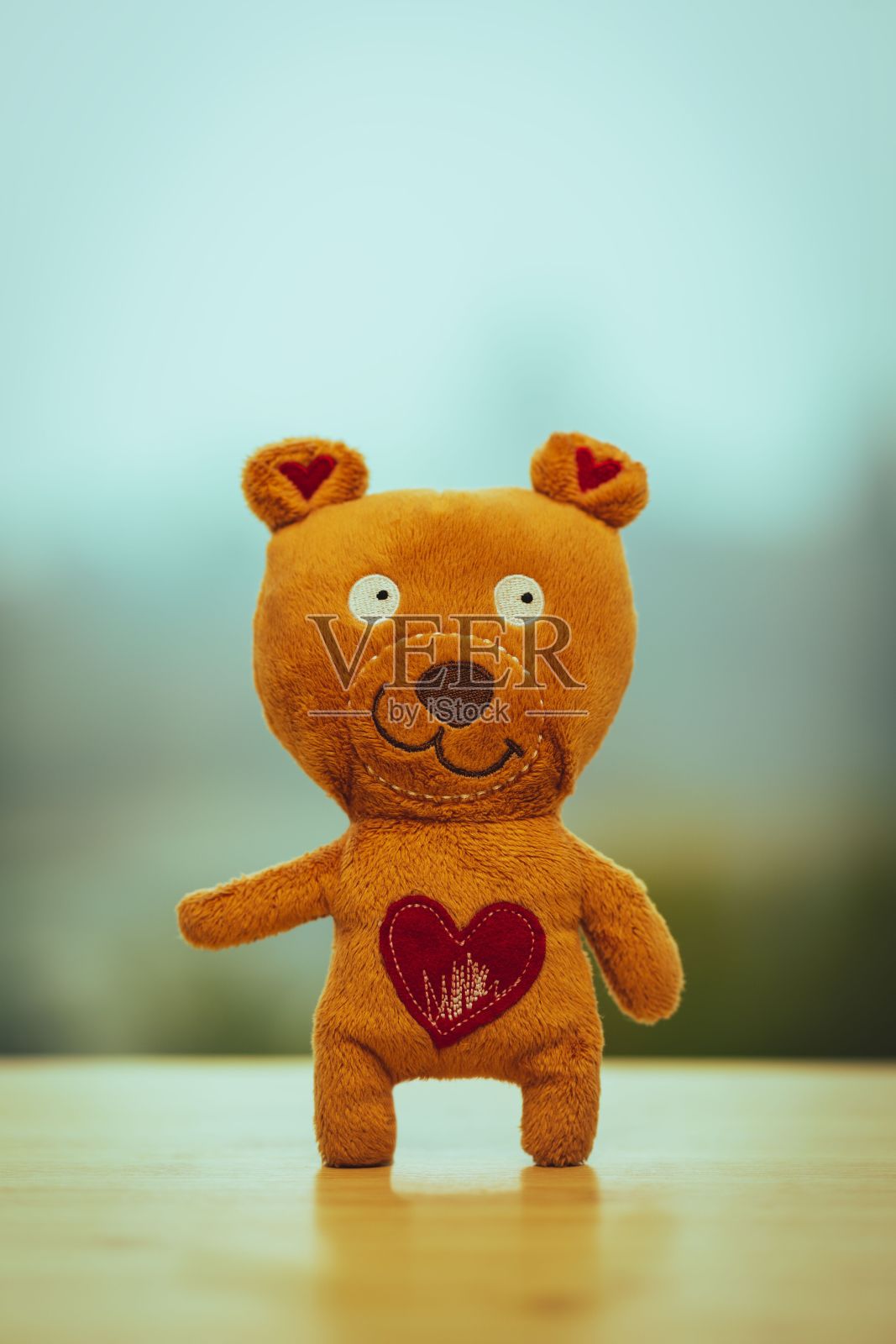 橙色的小泰迪熊，胸前有一个红色的心形补丁，表示爱和关心照片摄影图片