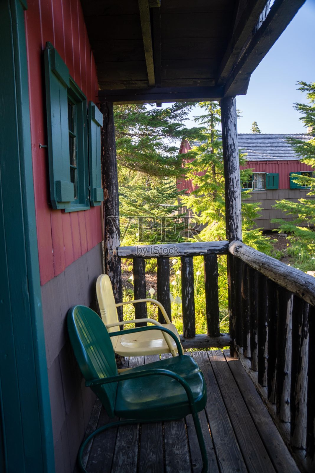 门廊里有一把椅子，可以俯瞰树林，还有一座红房子照片摄影图片