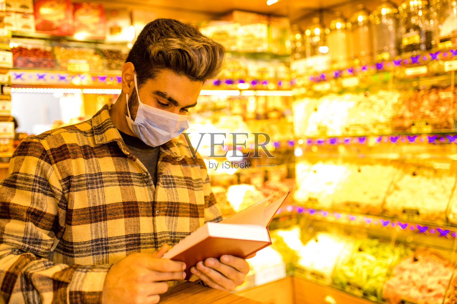 英俊的阿拉伯男子出售土耳其软糖安排伊斯坦布尔甜点杏仁，腰果和开心果商店街头市场摊位照片摄影图片