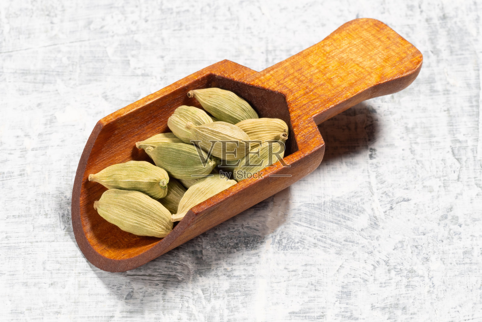 香料绿色小豆蔻(Elettaria cardamomum)在白色混凝土背景木勺。宏。烹饪概念的食材照片摄影图片