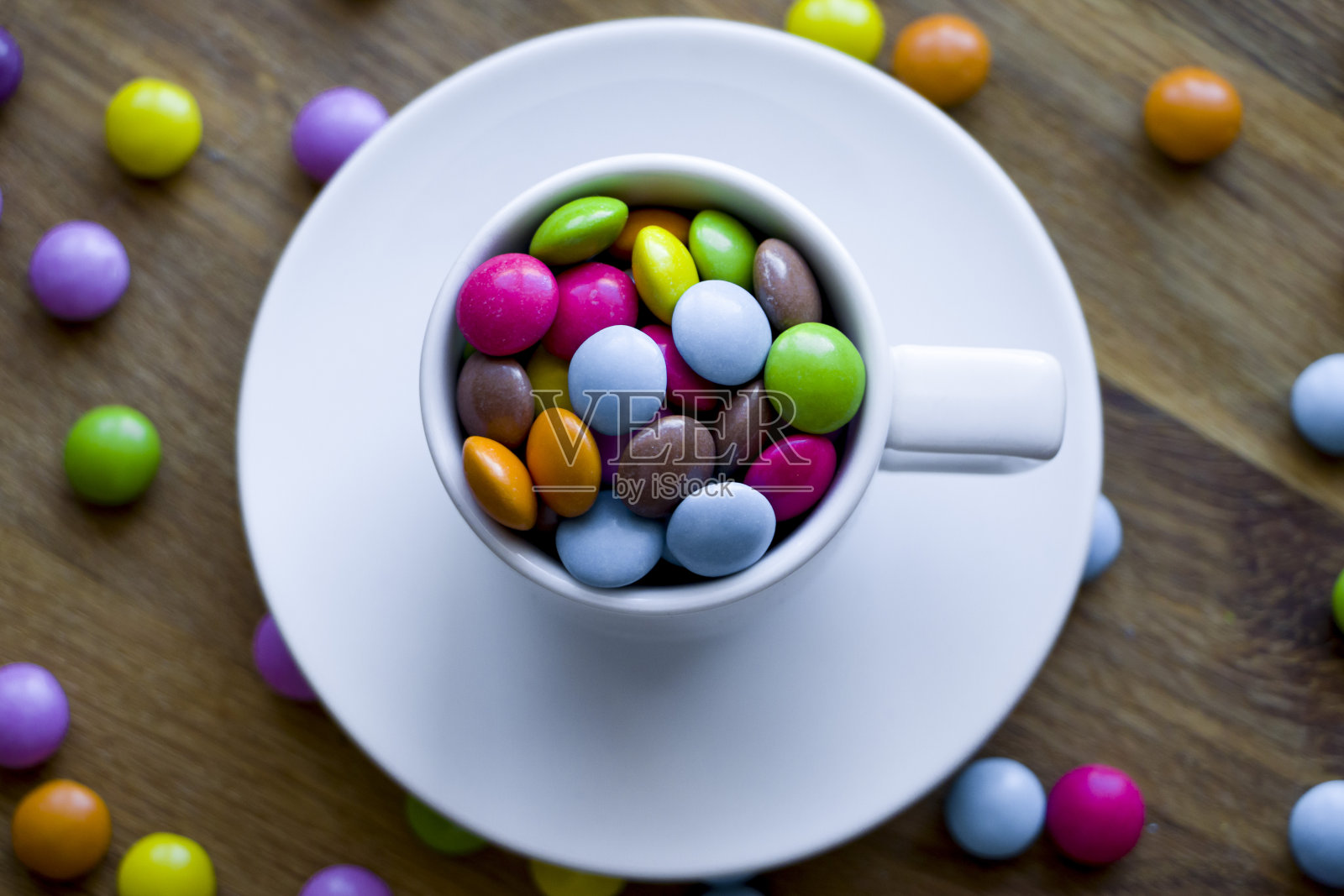 彩色多色的糖衣在一个白色的杯子里。照片摄影图片