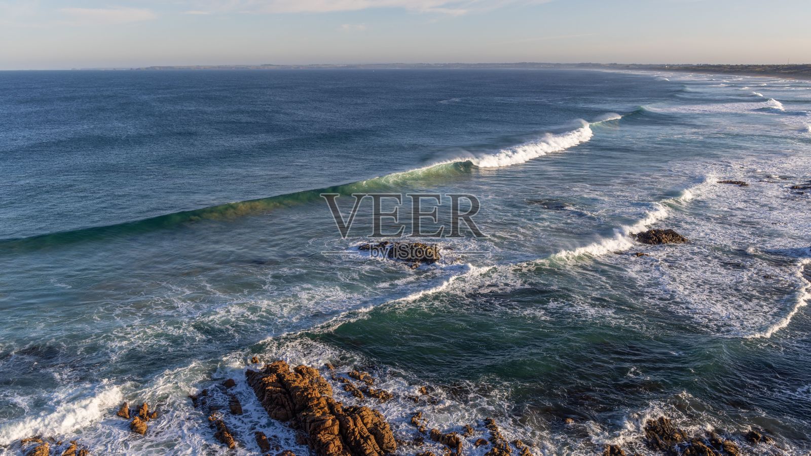 海浪冲到悬崖和天空前的岸边照片摄影图片