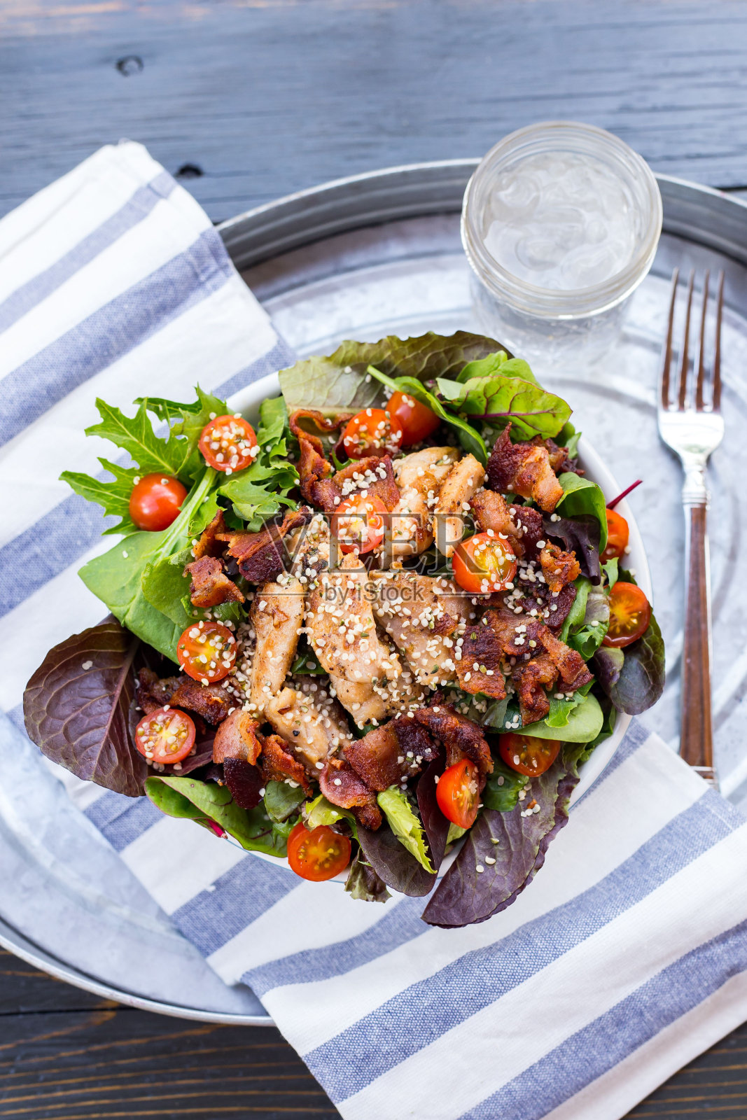 一盘充满活力的鸡肉生酮沙拉，旁边是一杯清澈的水。照片摄影图片