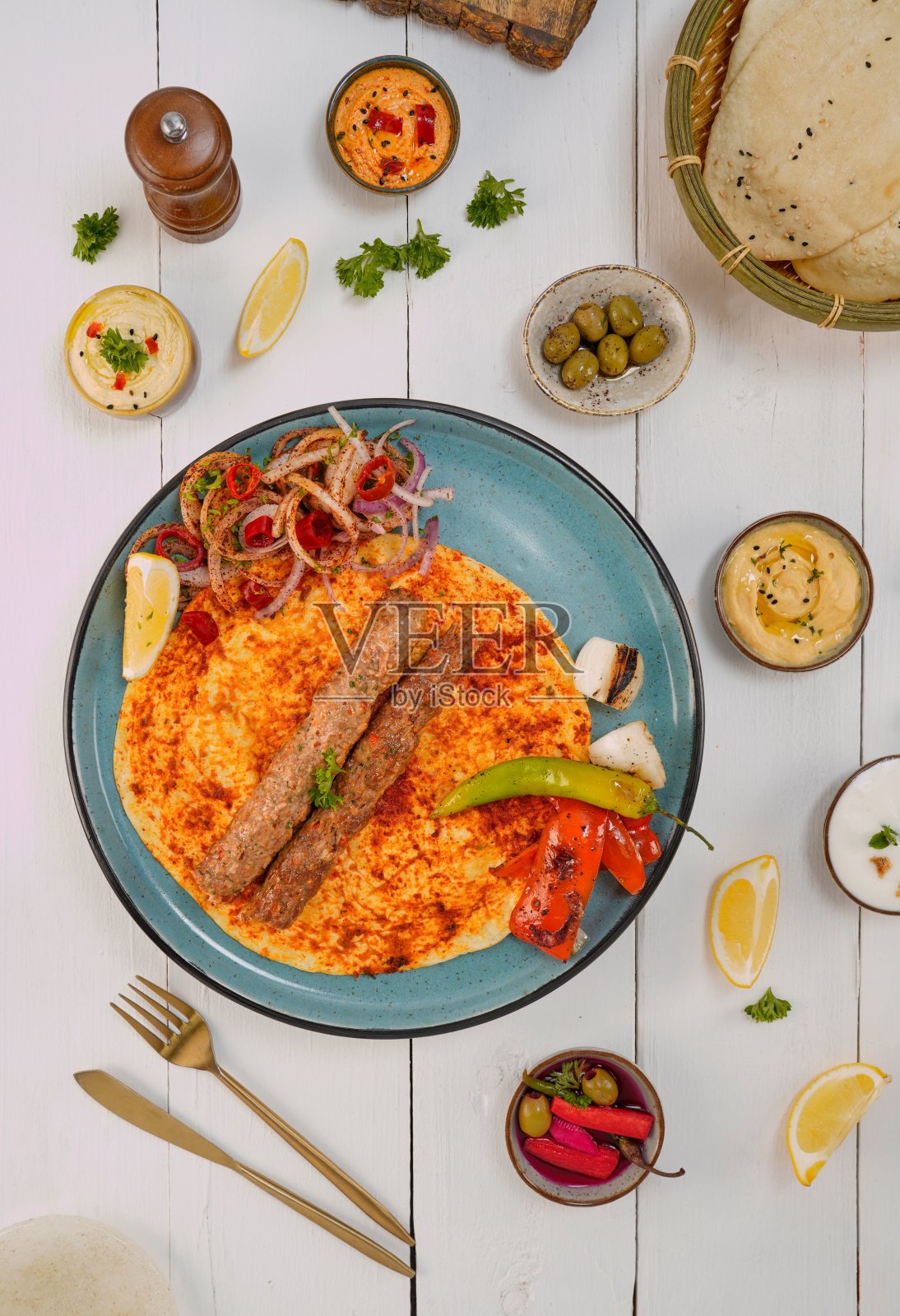 新鲜准备的烤肉串在一个蓝色的盘子与一系列的配菜和器具照片摄影图片