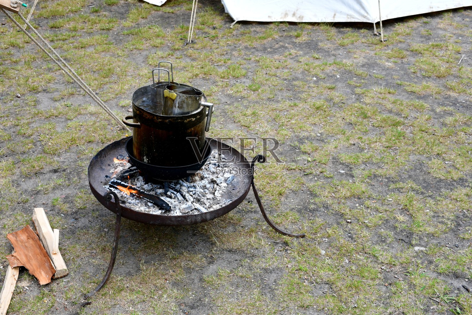 这是波兰一个多云的夏日，在田野上拍摄的一个由金属制成的小篝火，上面有一个支架，用来烧水、准备和烹饪香肠，以及做其他食物照片摄影图片