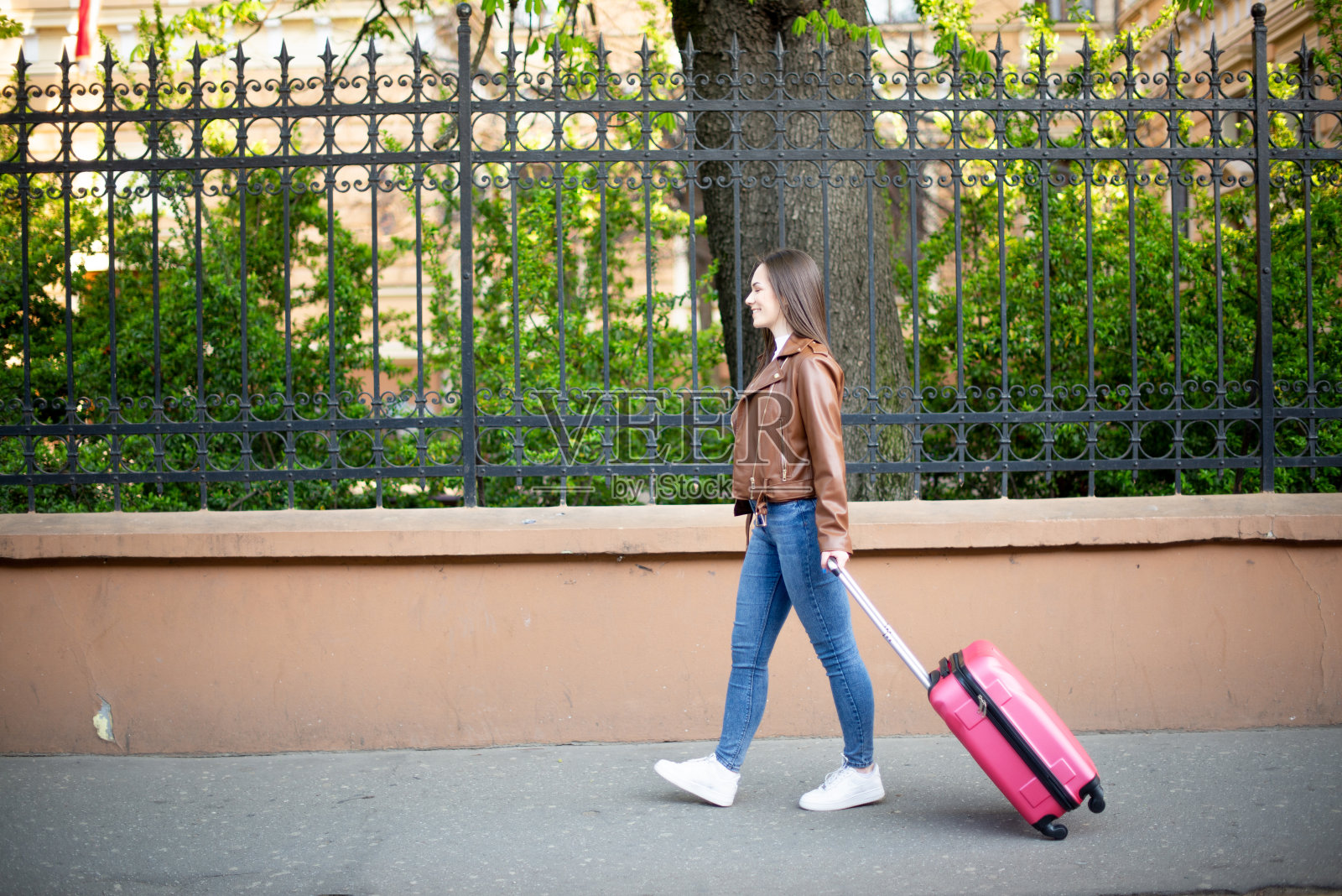 年轻女子提着行李箱走在街上照片摄影图片