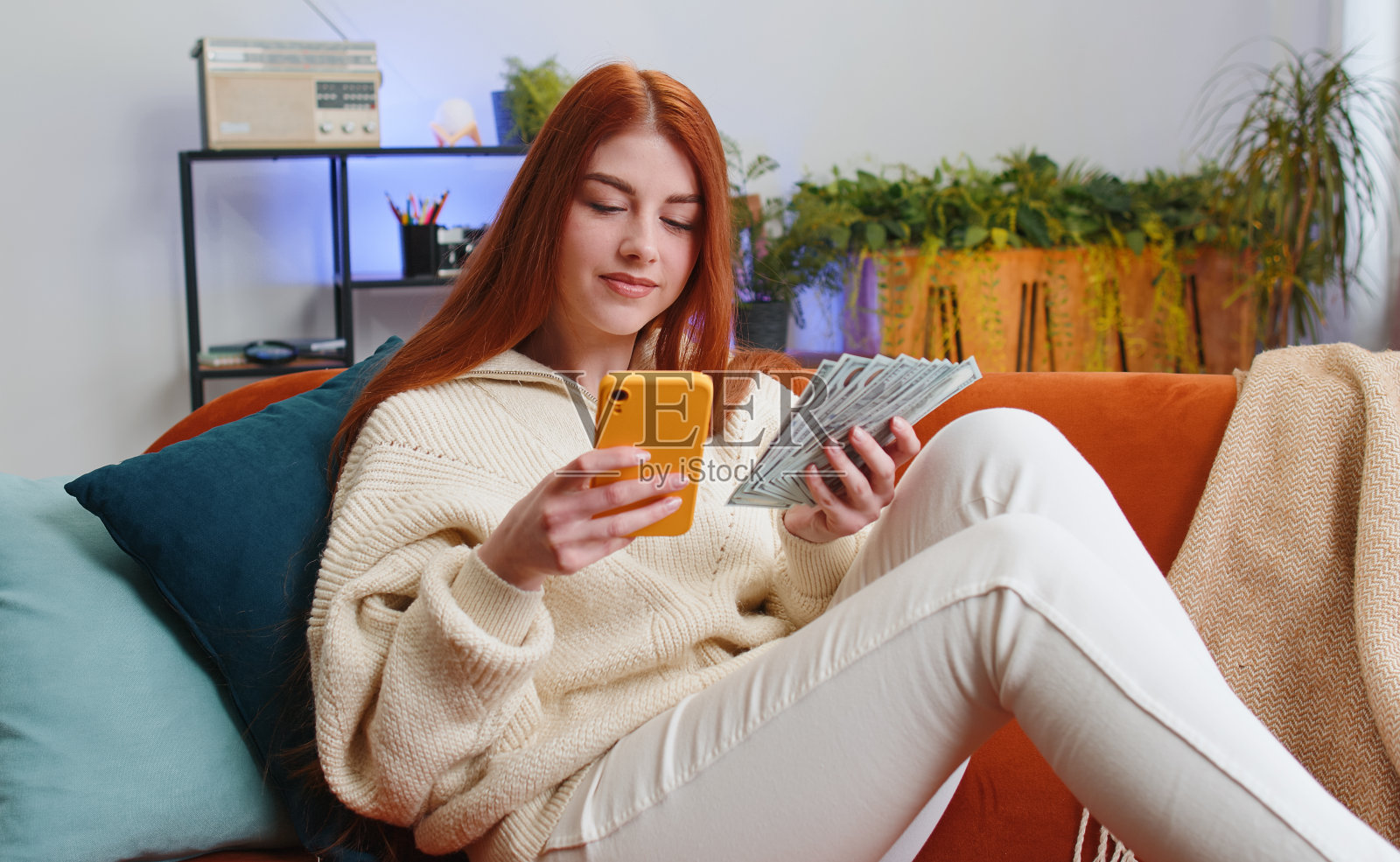 微笑快乐的年轻女子用智能手机计算现金收入节省了家里的彩票中奖预算照片摄影图片