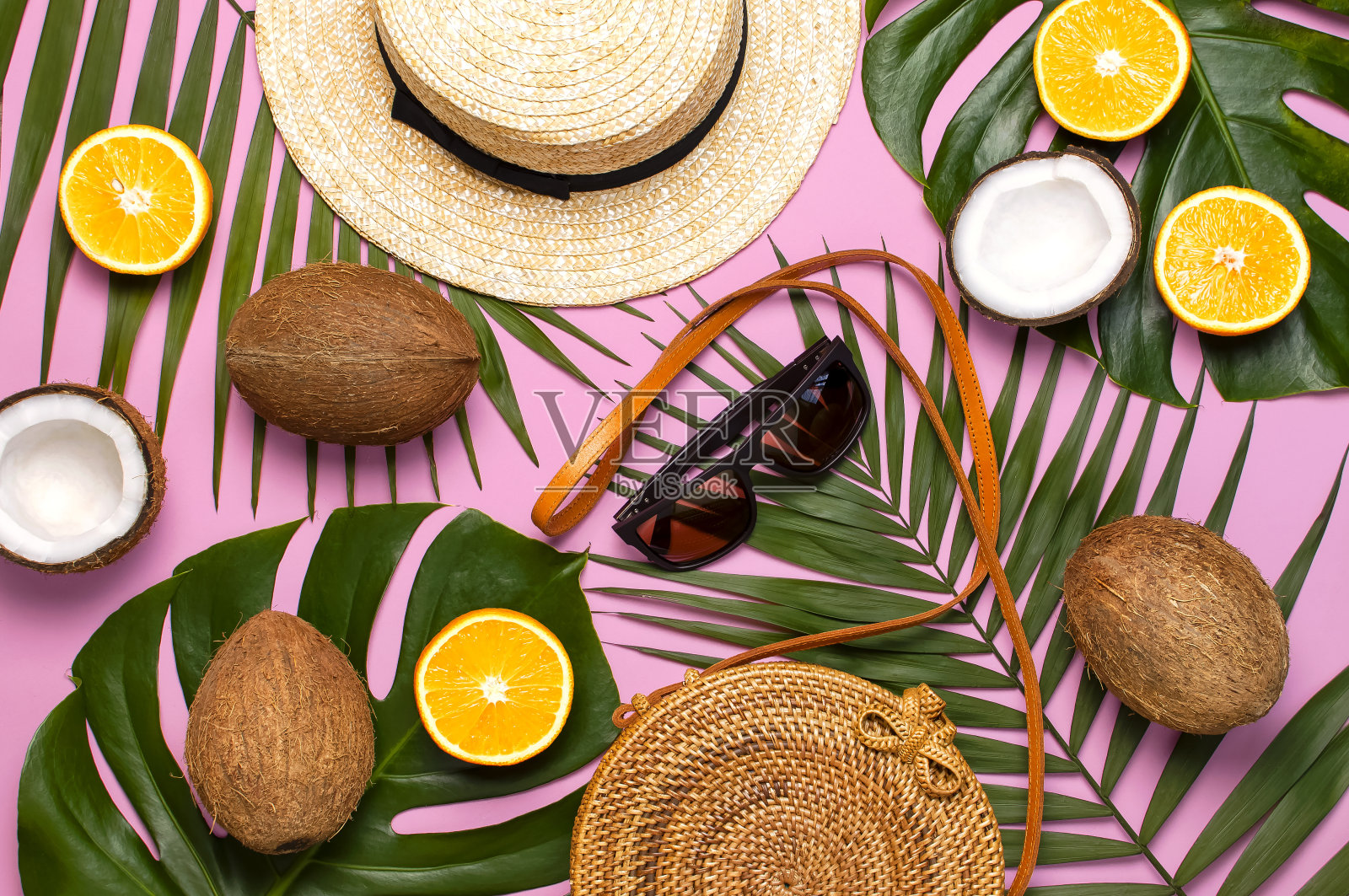 夏季时装平铺。圆形时髦的藤袋草帽太阳镜热带棕榈叶椰子橙在粉红色的背景。俯视图拷贝空间新潮竹袋创意背景度假概念照片摄影图片