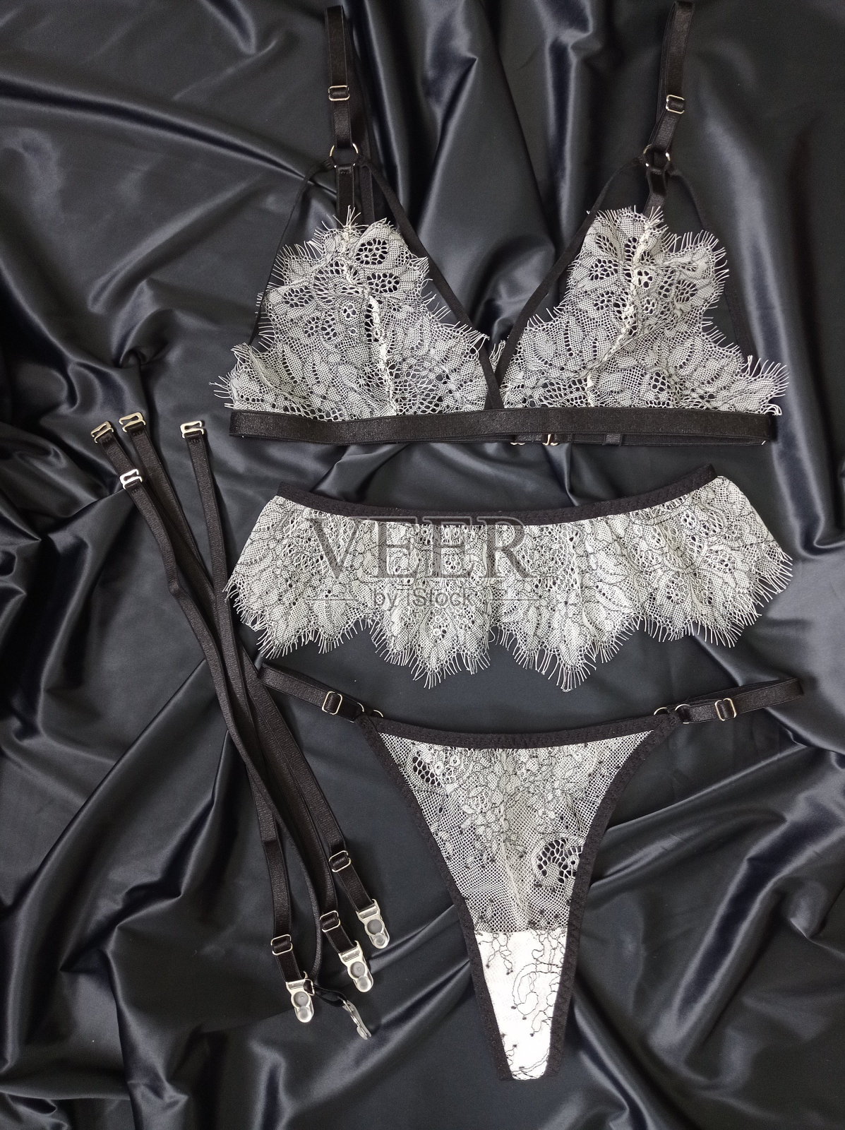一套由白色蕾丝制成的女性内衣。黑色背景。内衣配件。照片摄影图片