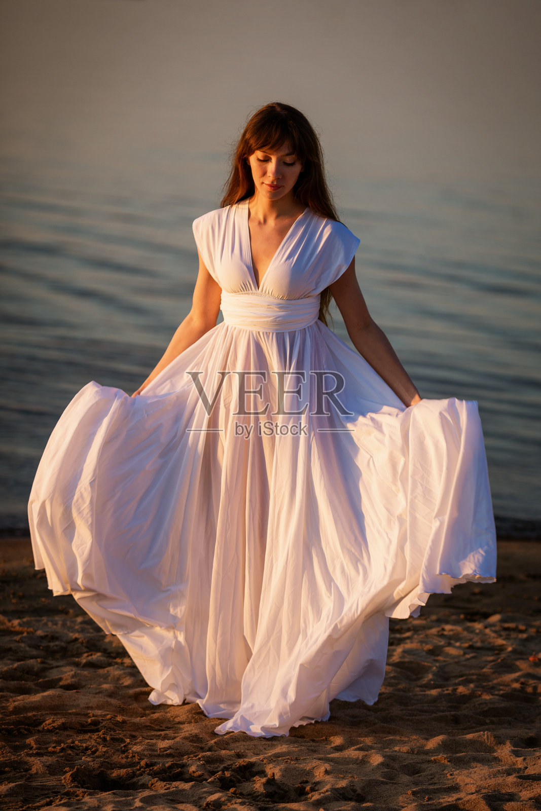 海滩上穿着白裙子的年轻女子照片摄影图片