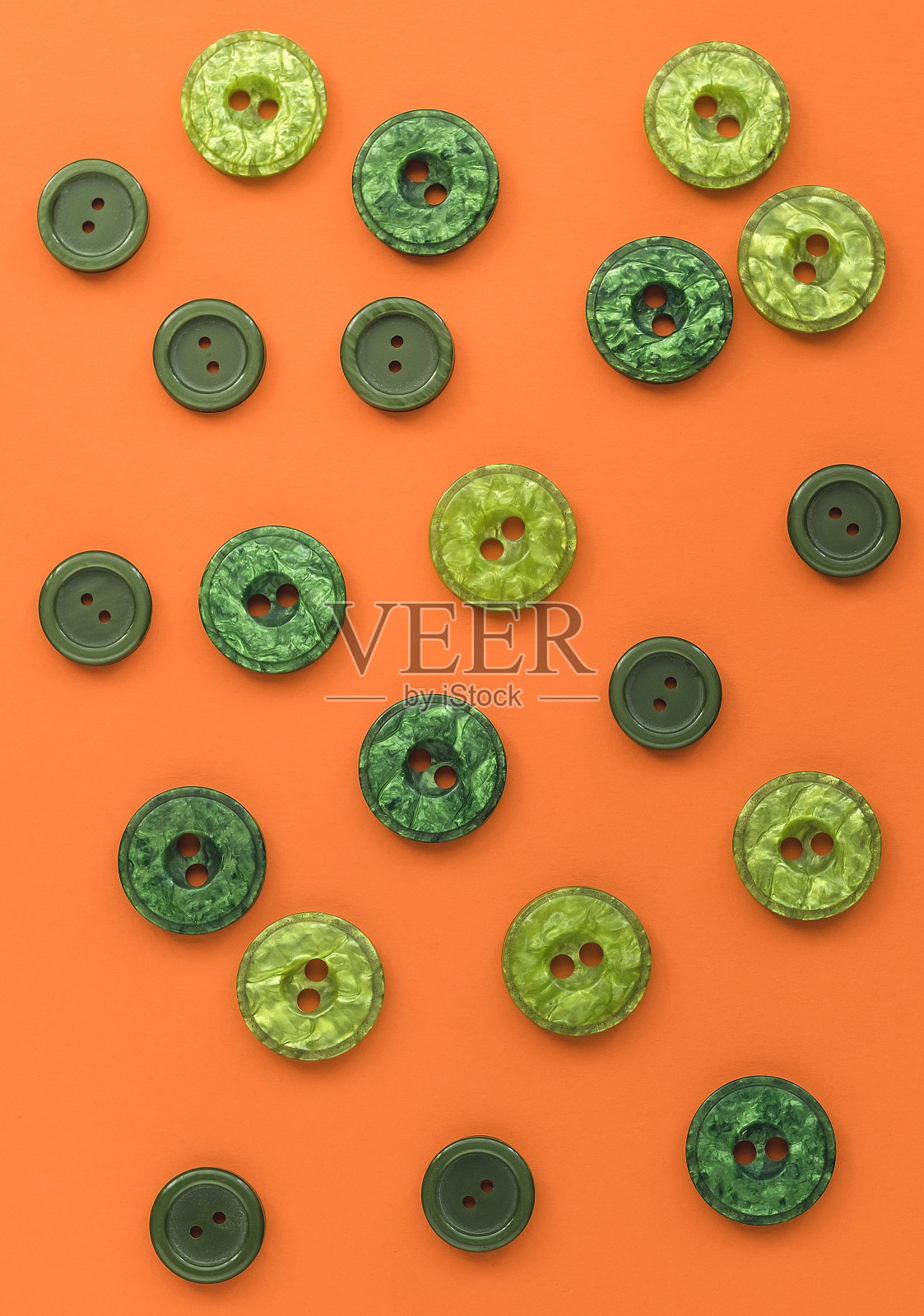 橙色背景上的许多绿色塑料按钮。缝纫按钮背景。前视图。照片摄影图片