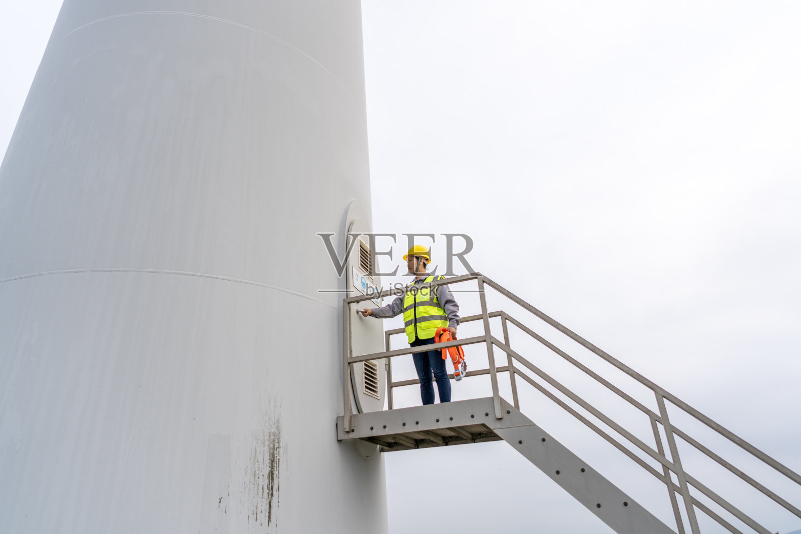 一名亚洲女工人正在爬风力涡轮机的梯子照片摄影图片