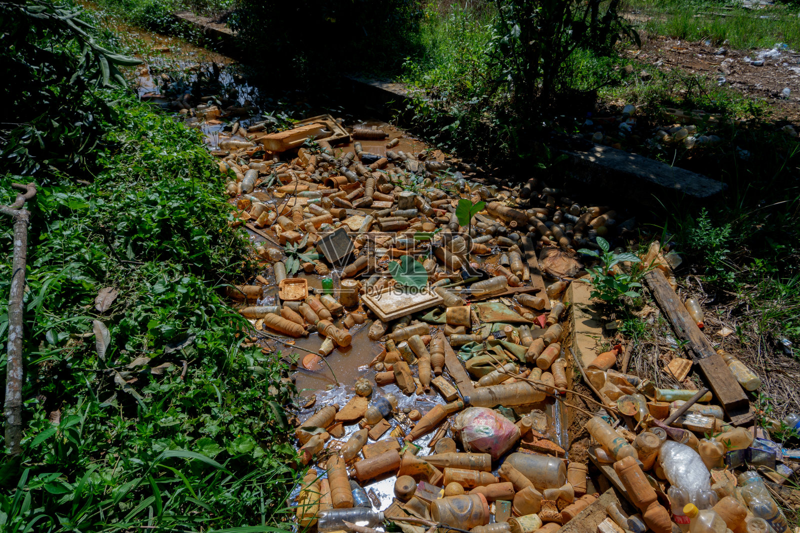 塑料饮料瓶留下的垃圾堆积在沟里，导致水堵塞而不流动，可能导致洪水照片摄影图片