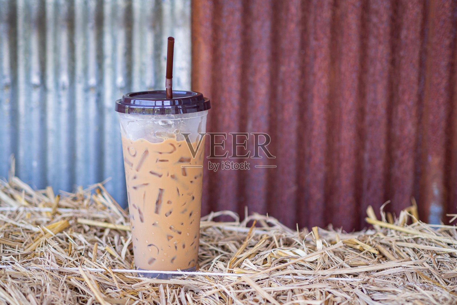 冰咖啡杯放置在吸管与镀锌墙。照片摄影图片