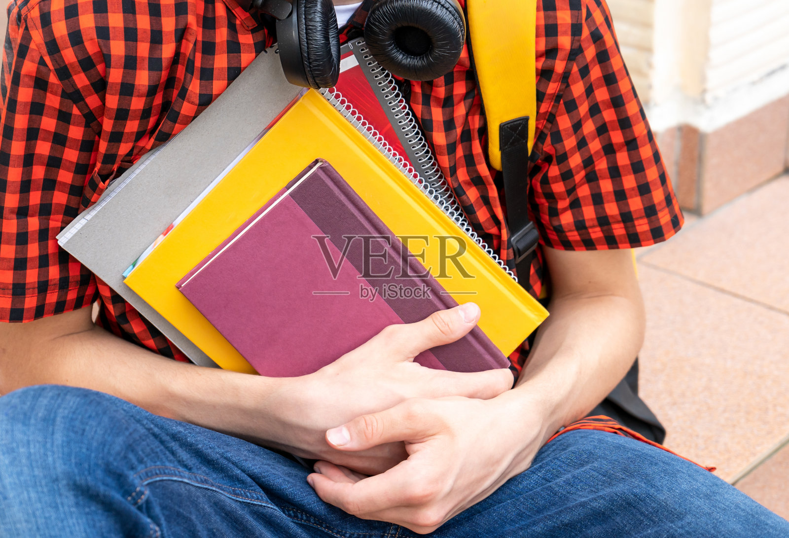 可爱的少年穿着红衬衫，背包里拿着笔记本，书在他的学校前面。回到学校背景。照片摄影图片