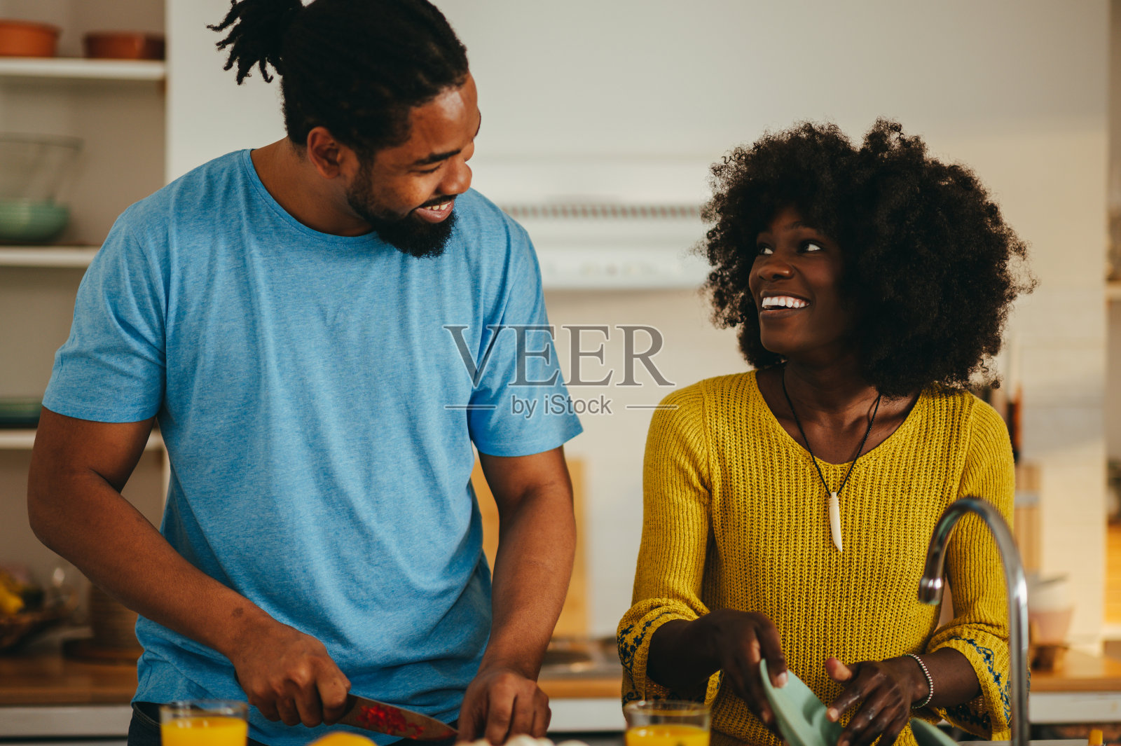 一对快乐的非裔美国夫妇正在家里做饭和洗碗。照片摄影图片