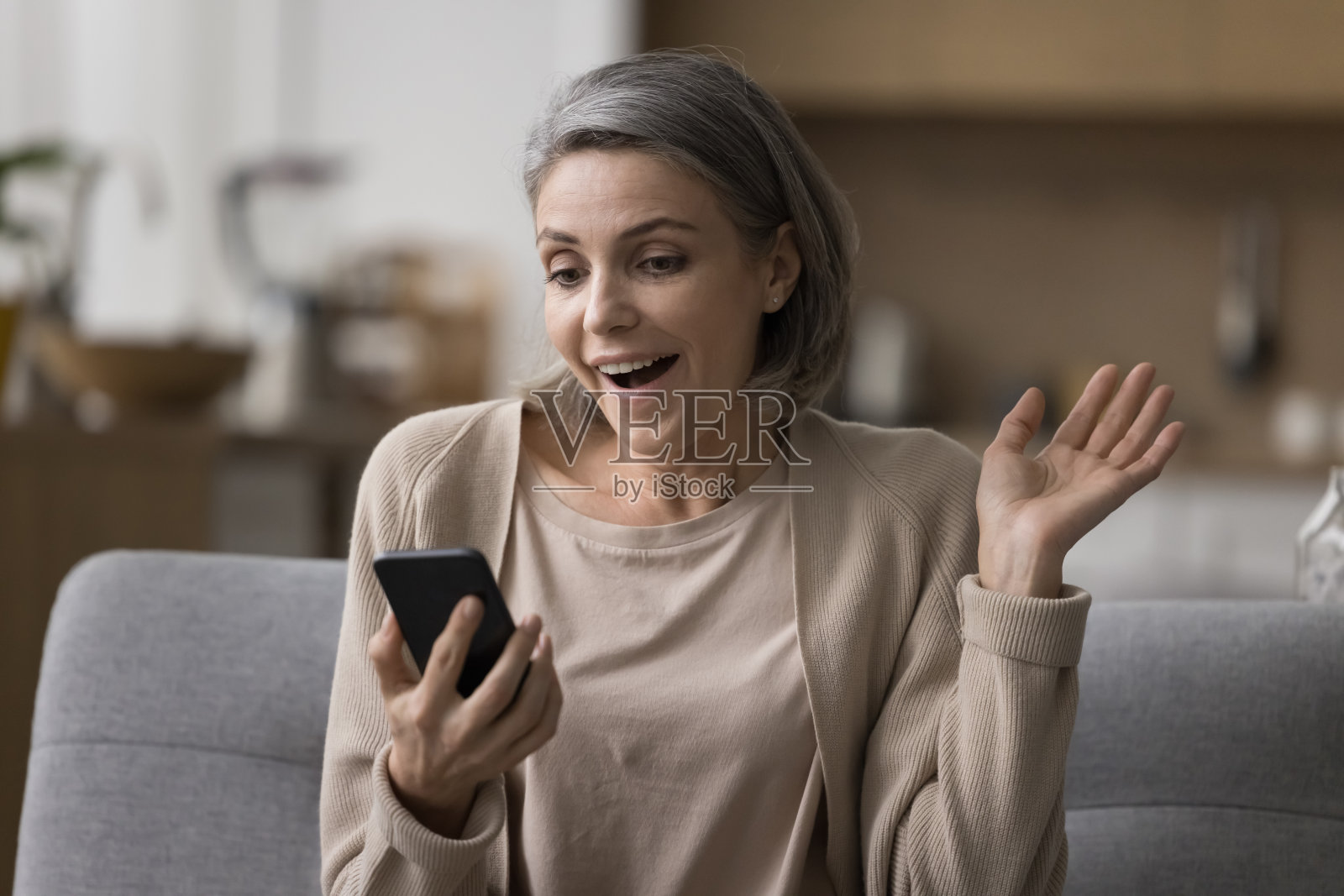 又惊又喜的成熟女人拿着智能手机，看着屏幕照片摄影图片