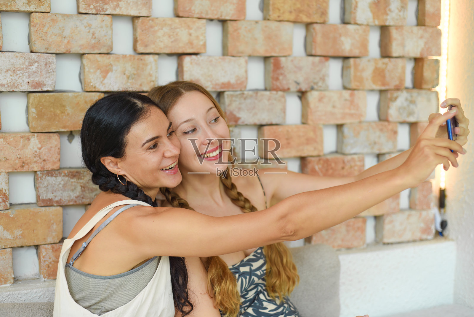 乌克兰女子(黑发)和俄罗斯女子(金发)梳着辫子摆姿势自拍照片摄影图片