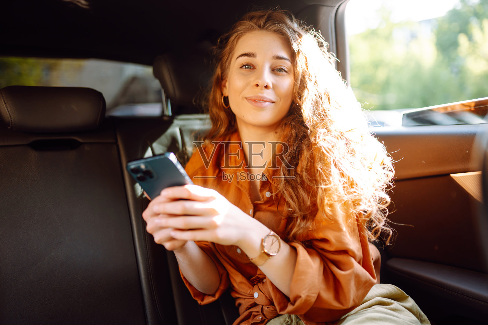 年轻女子在开车旅行时使用手机。照片摄影图片
