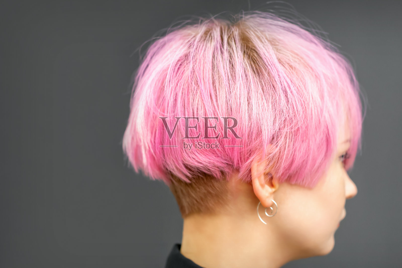 简介一个美丽的年轻白人妇女短鲍勃粉红色发型在深灰色的背景。照片摄影图片