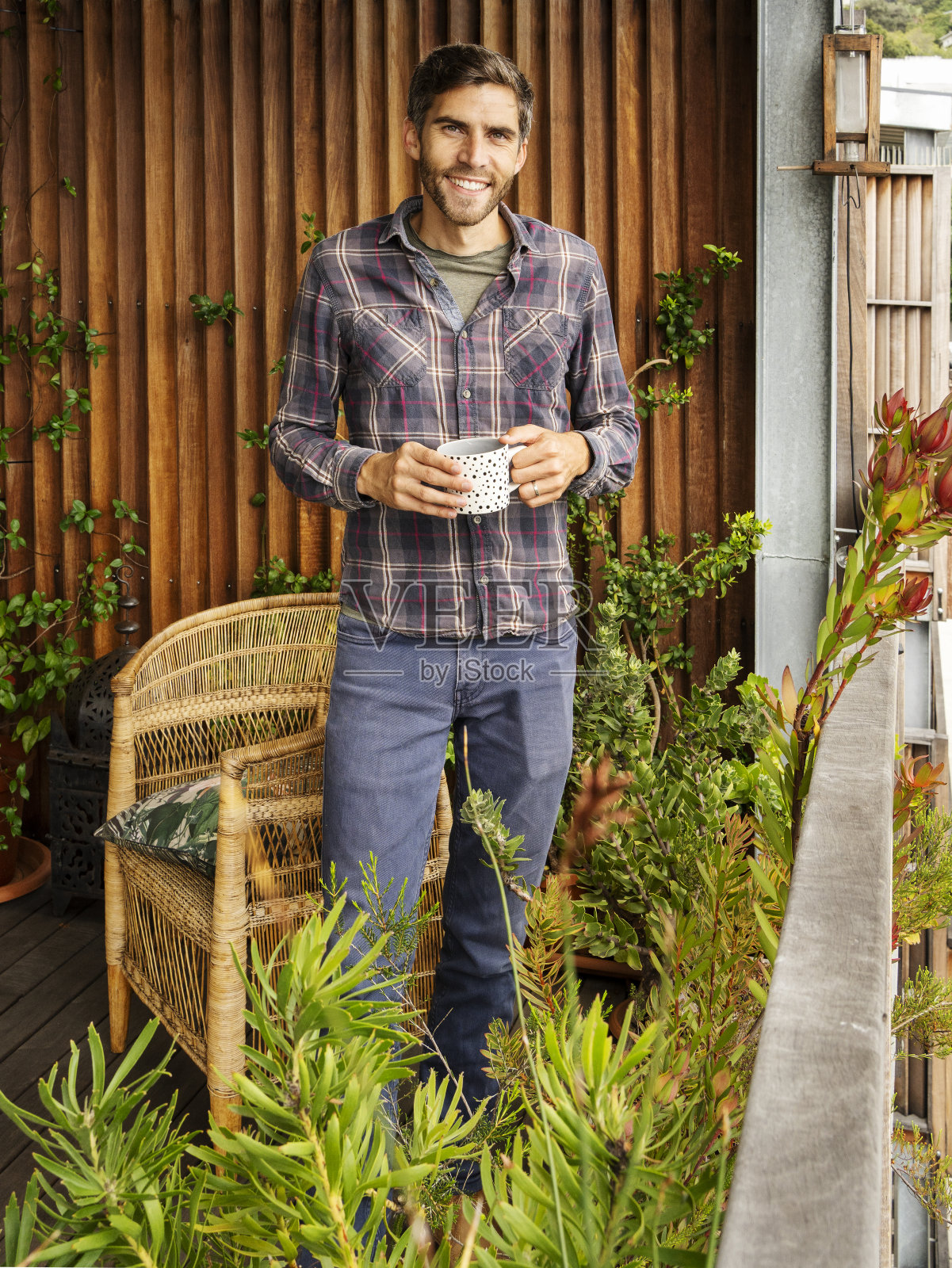 微笑的年轻人在他公寓的露台上喝咖啡照片摄影图片