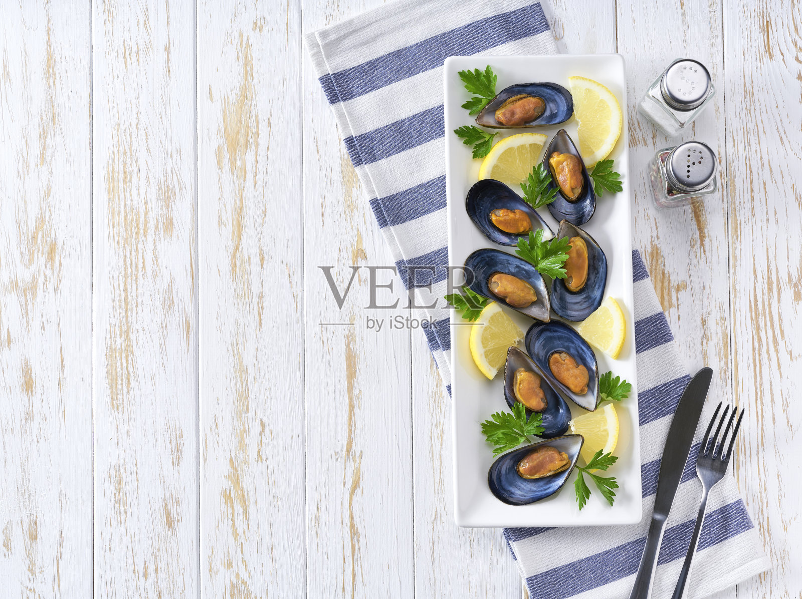 海鲜贻贝与柠檬和欧芹在轻型桌面，顶视图，复制空间为您的文字。照片摄影图片