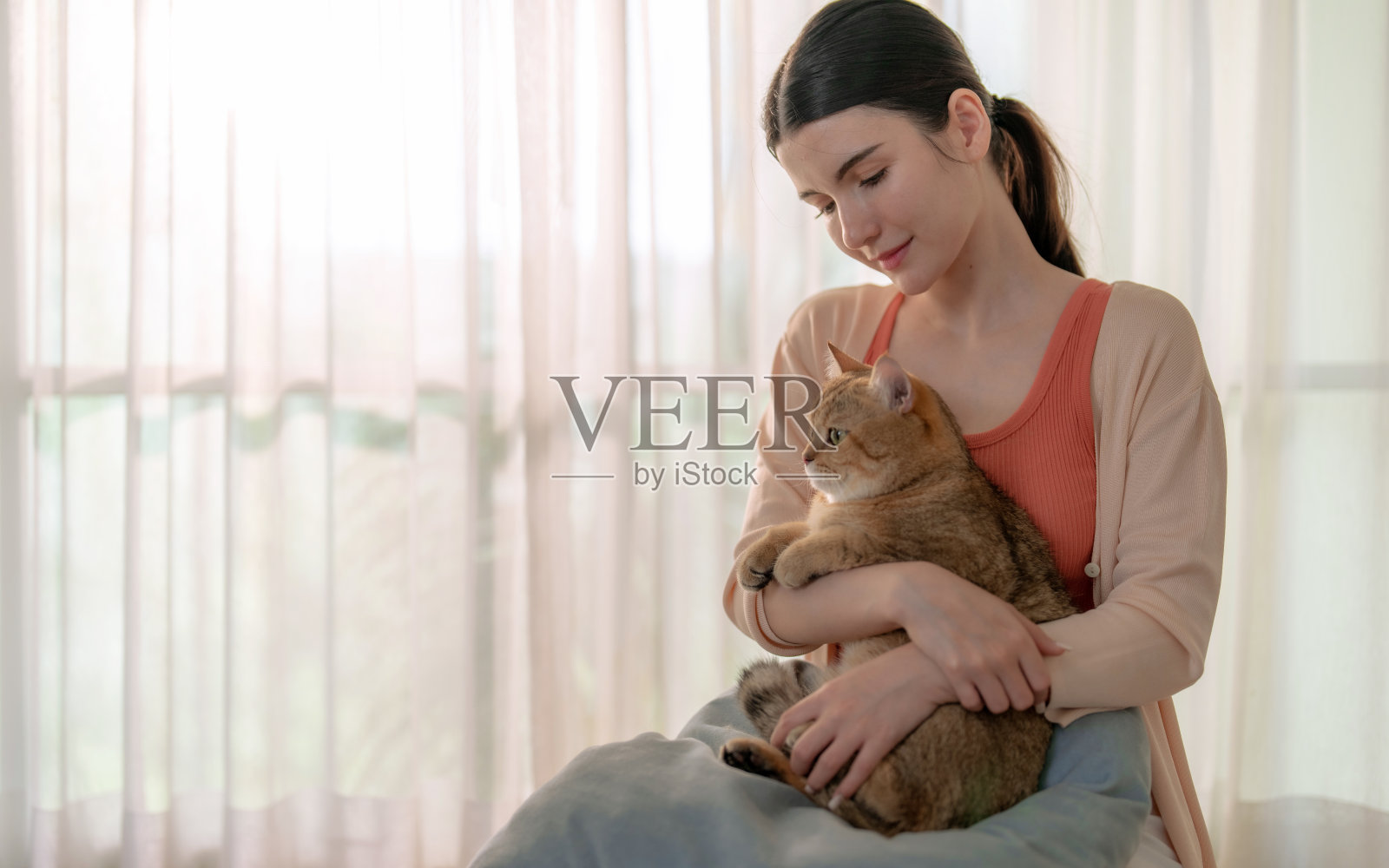 快乐的亚洲妇女享受在家里玩她可爱的宠物。照片摄影图片