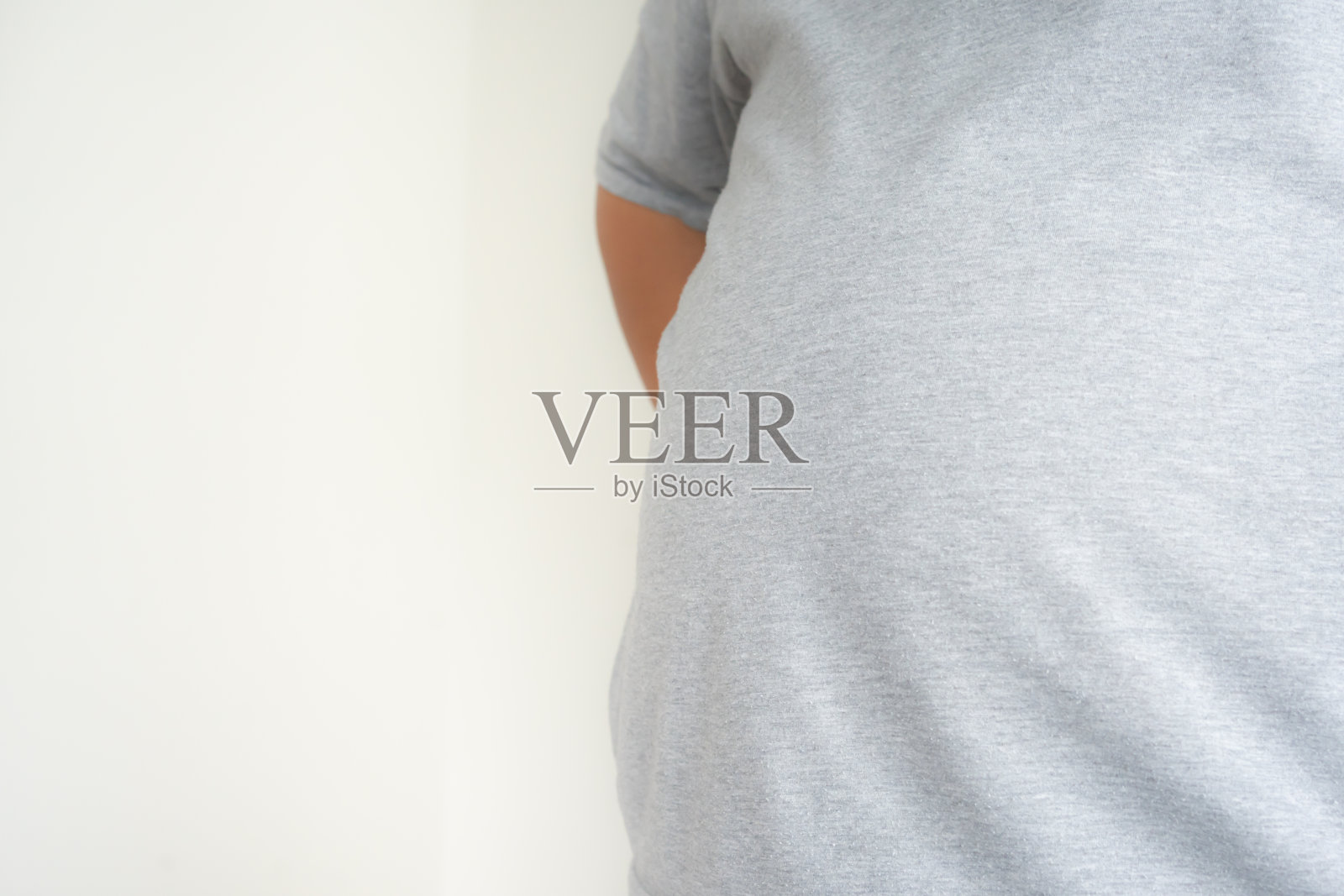 又大又胖的男人穿着普通的衣服站着展示真实的尺寸。照片摄影图片