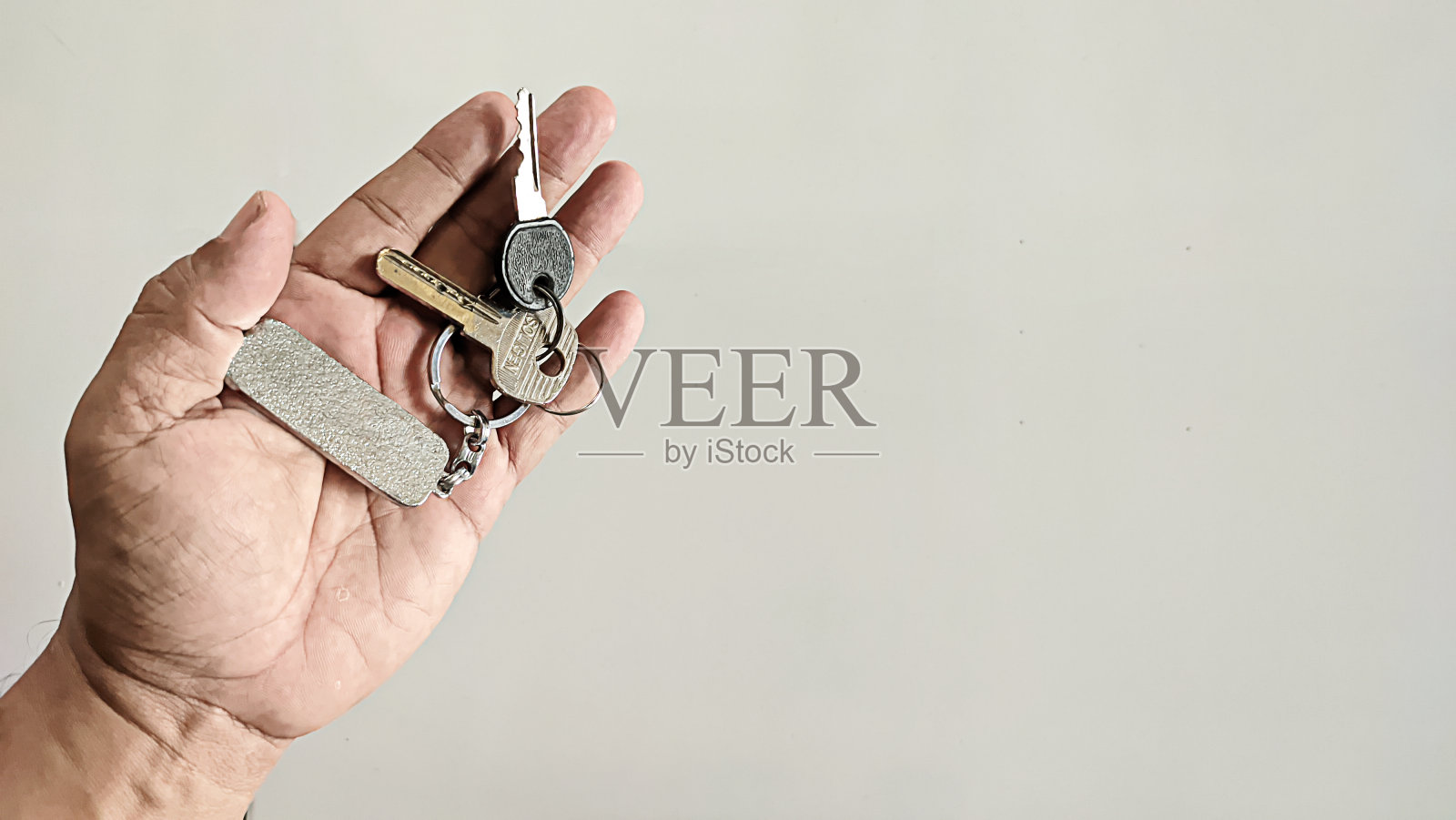 一个男人手里拿着两把钥匙和一个钥匙链照片摄影图片