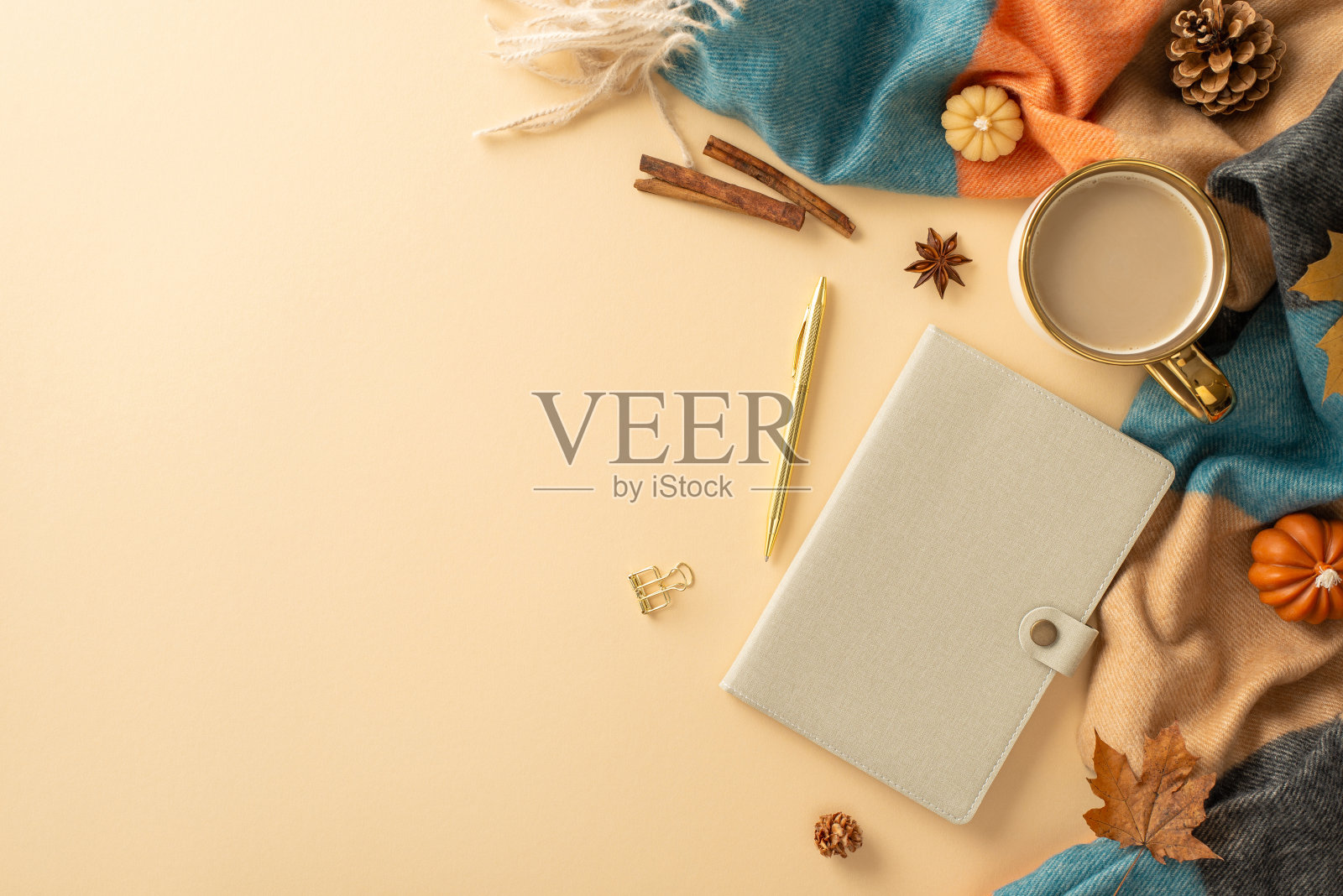 带有秋天气息的季节性办公桌概念。俯视图的热咖啡杯，规划师在皮革封面，文具，温暖的格纹，微型南瓜等软米色背景，留出空间的广告照片摄影图片