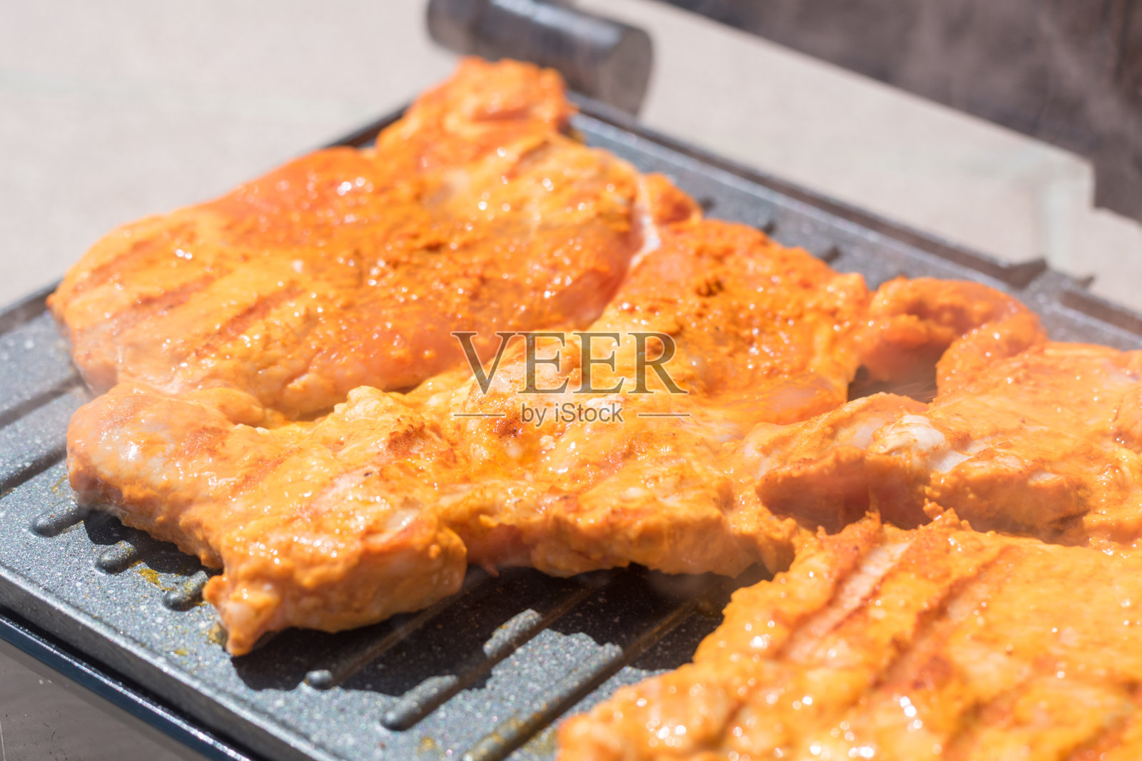 用电烤炉烤牛排。烤着美味的猪臀片。照片摄影图片