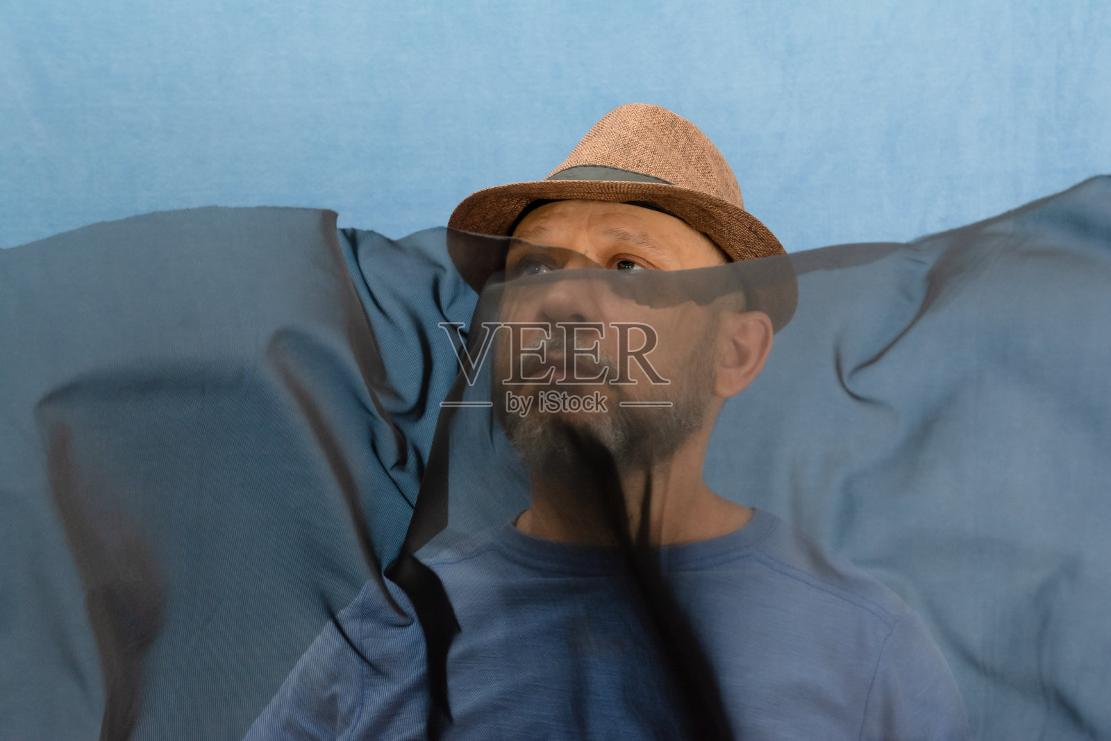 戴着帽子的男子和留着胡子的男子正在摆弄一块透明的黑色布料。照片摄影图片