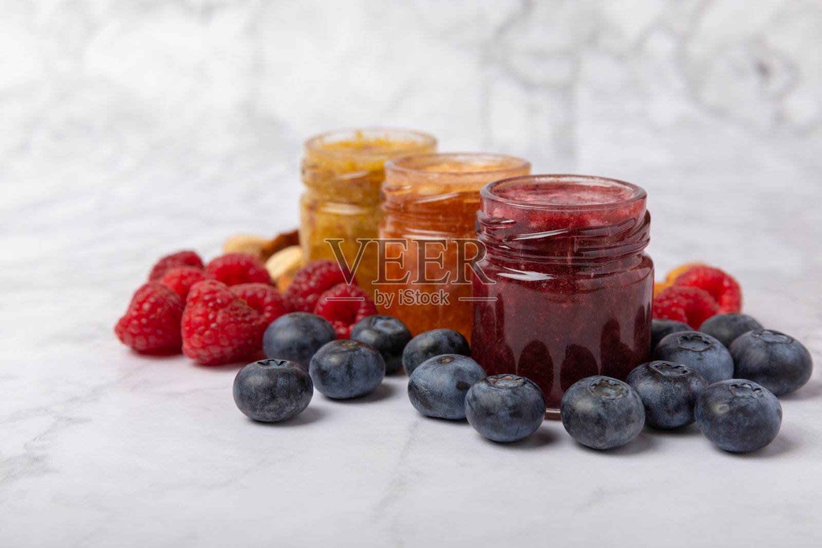 一罐蜂蜜。水果蜂蜜配覆盆子、蓝莓、杏仁和开心果。健康和美丽的果酱。蜂蜜膏。素食的有机产品。副本的空间。复制空间，一罐蜂蜜。水果蜂蜜配覆盆子，蓝莓，杏仁和葡萄照片摄影图片