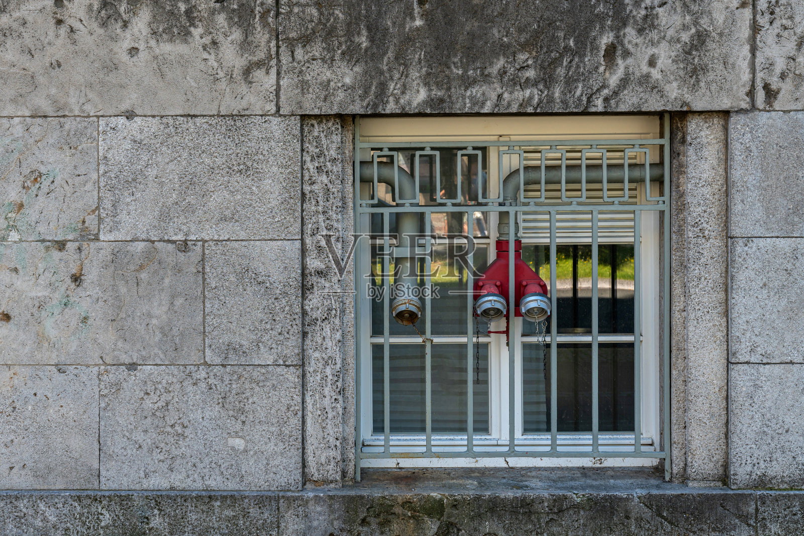 建筑物的铁条窗户和里面连接的消防水龙头。照片摄影图片