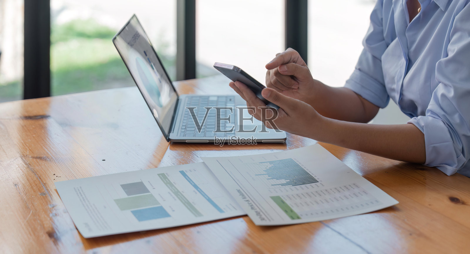 女性手持智能手机在笔记本电脑上获取信息并确认交易，女性使用手机应用程序照片摄影图片