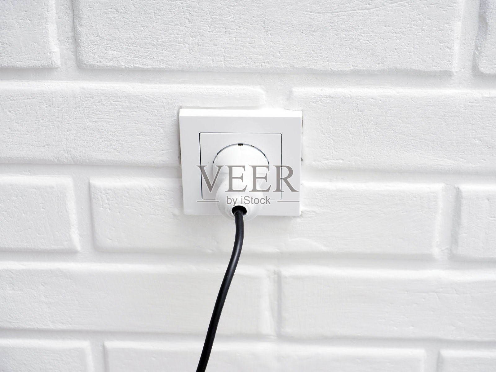 电源插头和插座以白色砖墙为背景，电源节能理念照片摄影图片